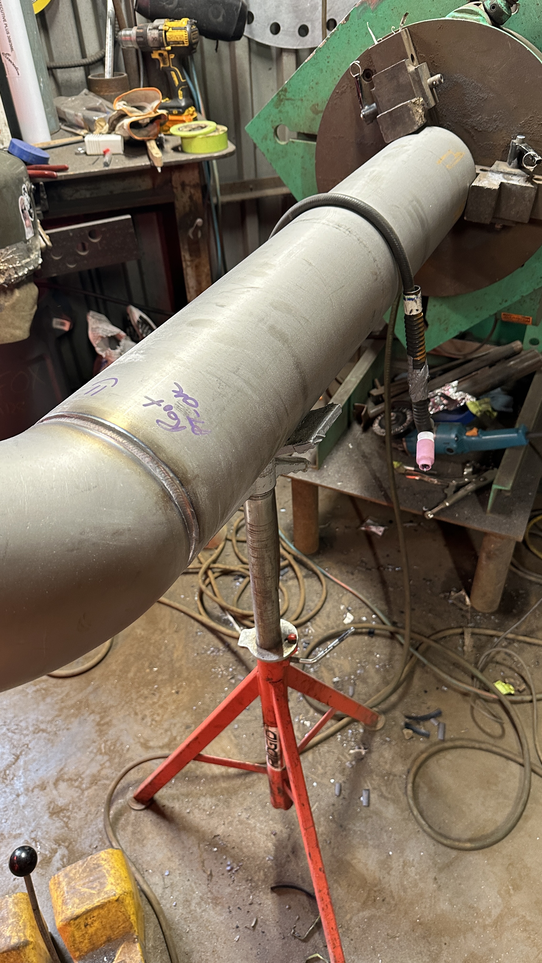 TIG welding setup on a stainless steel pipe assembly in a fabrication shop